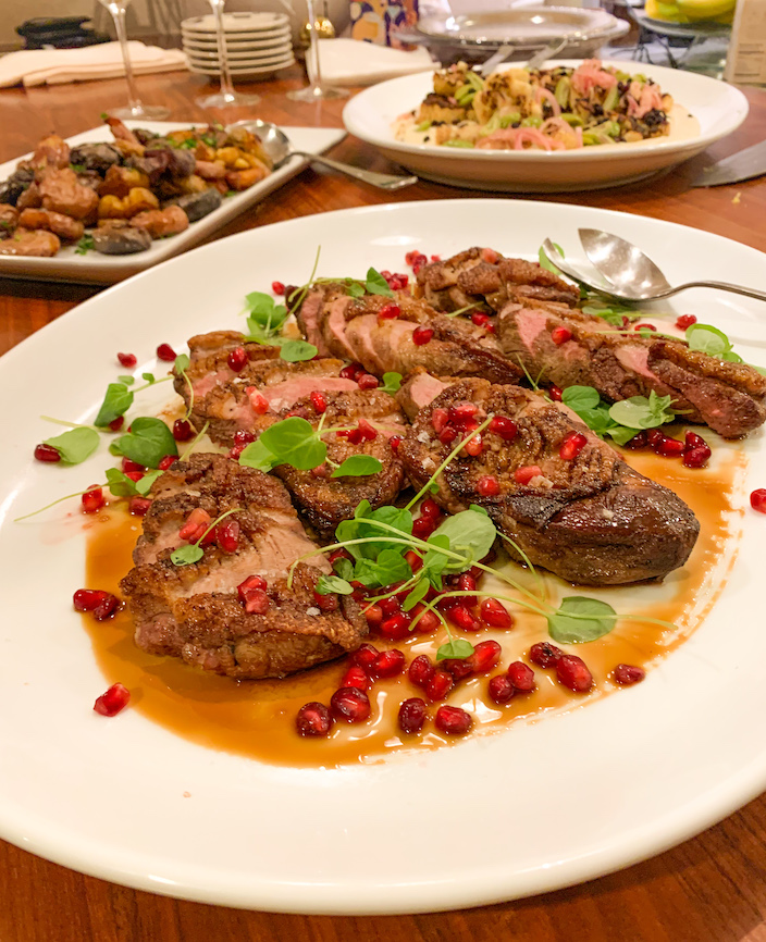Event platter of sliced meat with pomegranate and fresh herbs